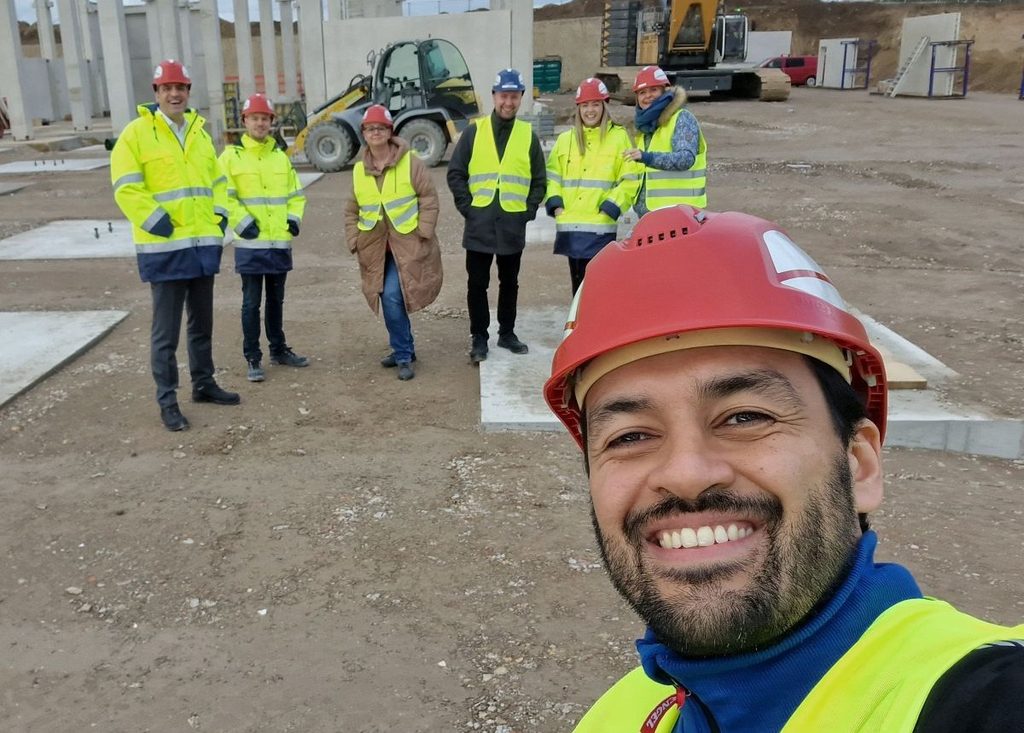Felipe and colleagues wearing safety helmets and high-visibility clothing at a construction site.
