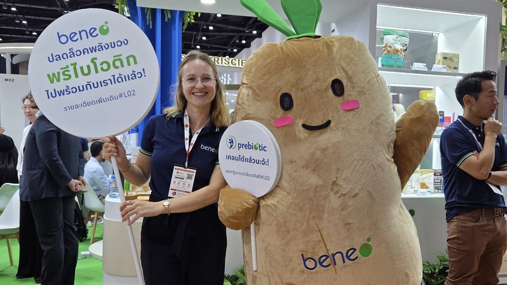 Noëmie beside a chicory root mascot at the BENEO stand at Fi Asia 2025 in Bangkok.
